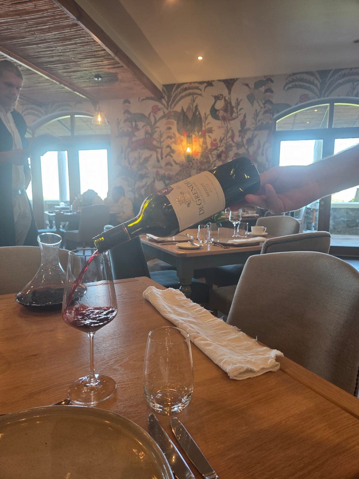 Wine being poured at an upscale restaurant table during a guest-experience visit